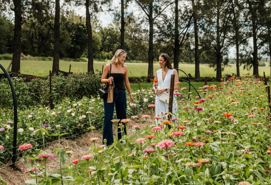 Eat Local Month Two Ladies Walking between flower beds Farm Gate Trail